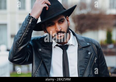 Ein bärtiger Inder mit schwarzem Hut geht die Straße hinunter. Stockfoto