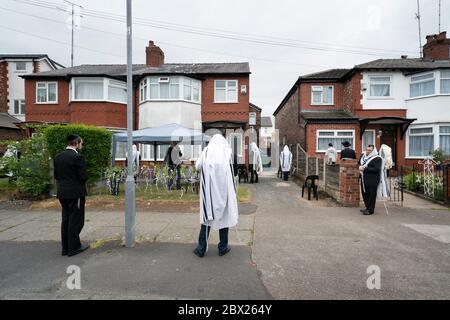 Manchester, Großbritannien. Juni 2020. Orthodoxe jüdische Männer führen ihre Morgengebete in angrenzenden Gärten in Salford, um die neuen Regeln zu erfüllen, die es 6 Menschen ermöglichen, sich in einem Garten zu versammeln, aber dennoch einen Minyan zu erreichen, ein Quorum von zehn jüdischen Erwachsenen, die für bestimmte religiöse Verpflichtungen erforderlich sind, Manchester, Großbritannien. Kredit: Jon Super/Alamy Live News. Stockfoto