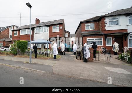 Manchester, Großbritannien. Juni 2020. Orthodoxe jüdische Männer führen ihre Morgengebete in angrenzenden Gärten in Salford, um die neuen Regeln zu erfüllen, die es 6 Menschen ermöglichen, sich in einem Garten zu versammeln, aber dennoch einen Minyan zu erreichen, ein Quorum von zehn jüdischen Erwachsenen, die für bestimmte religiöse Verpflichtungen erforderlich sind, Manchester, Großbritannien. Kredit: Jon Super/Alamy Live News. Stockfoto