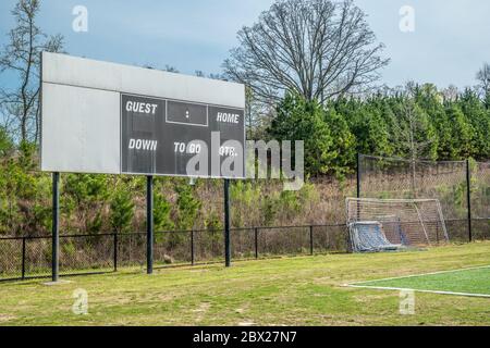 Leere und ungenutzte Anzeigetafel auf einem Fußballfeld in einem Park mit Tornetzen Bäume und Fechten im Hintergrund in einem Park im frühen Frühjahr Stockfoto