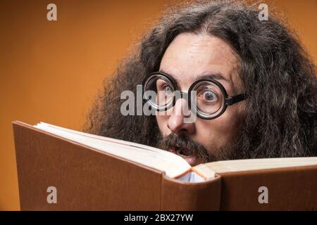 Porträt eines lustigen Nerds, der ein Buch liest Stockfoto