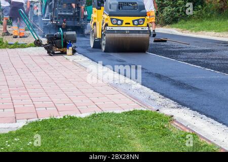 Frischer schwarzer Asphalt auf neuer Straße. Bauarbeiten am Arbeitsplatz. Stockfoto