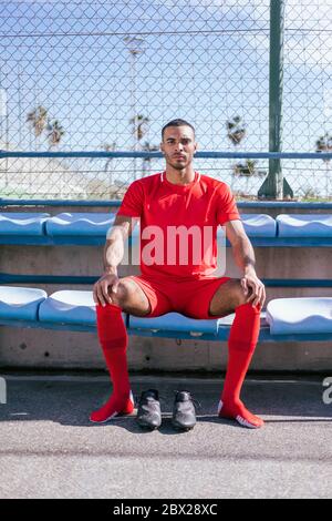 Porträt eines afroamerikanischen Fußballspielers auf der Bank Stockfoto