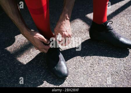 Nahaufnahme der Füße des Fußballspielers, die seine Stiefel fixieren Stockfoto