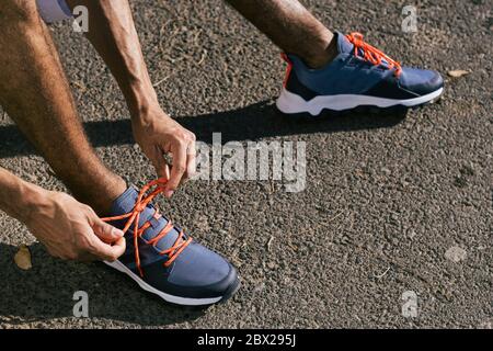 Nahaufnahme des männlichen Athleten, der Sportschuhe Schnürsenkel bindet Stockfoto