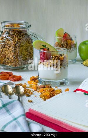 Zwei Portionen in transparenten Tassen hausgemachtes Müsli mit Joghurt, Nüssen und getrockneten Früchten Stockfoto