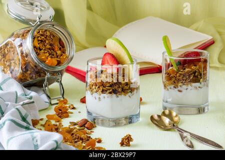 Zwei Portionen in transparenten Tassen hausgemachtes Müsli mit Joghurt, Nüssen und getrockneten Früchten Stockfoto