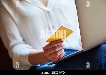 Nahaufnahme einer jungen Frau, die online mit Kreditkarte auf einem Laptop einkauft und bezahlt. Stockfoto