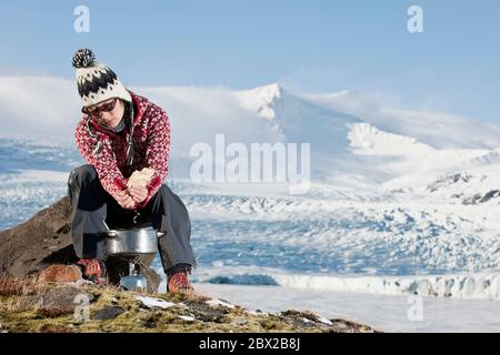 Frau, die draußen in winterlicher Landschaft kocht Stockfoto