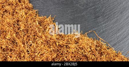 Getrocknete zerfetzte Hand rollenden rauchenden Tabak auf einem Steinschiefer Hintergrund Stockfoto