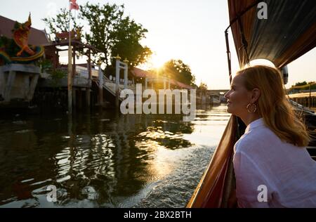 Eine Frau, die von einem langen Boot in Bangkok aus Sightseeing Stockfoto