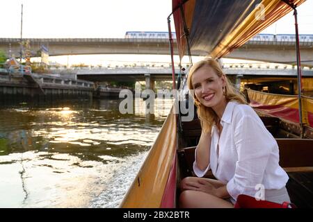 Eine Frau, die von einem langen Boot in Bangkok aus Sightseeing Stockfoto