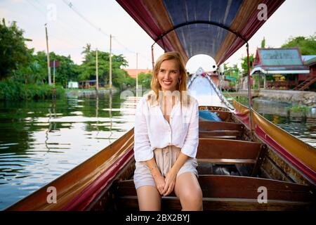 Eine Frau, die von einem langen Boot in Bangkok aus Sightseeing Stockfoto