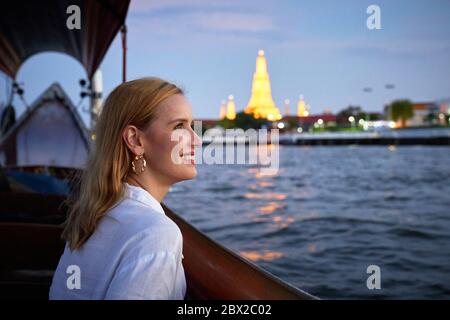 Eine Frau, die von einem langen Boot in Bangkok aus Sightseeing Stockfoto