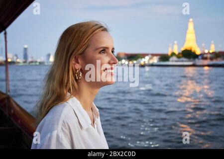 Eine Frau, die von einem langen Boot in Bangkok aus Sightseeing Stockfoto