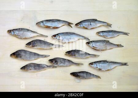 Ausgekleidete getrocknete Fischmuster auf einer Holzoberfläche. Getrocknete Fisch Produkt Hintergrund Textur. Stockfoto