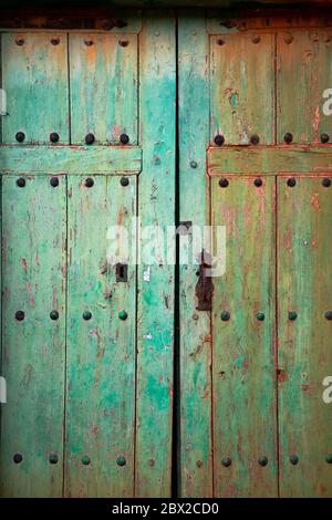 Alte rustikale Holztür mit verschiedenen Schichten von gebrochenen Farbe in grün und orange Farben Stockfoto