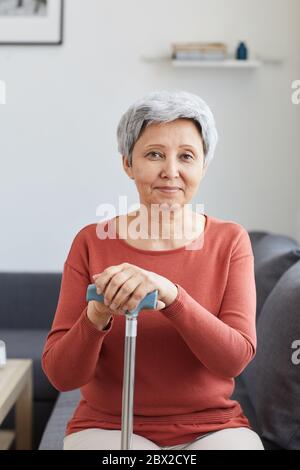 Porträt einer älteren Frau, die sich auf dem Sofa ausruht und die Kamera im Wohnzimmer anschaut Stockfoto