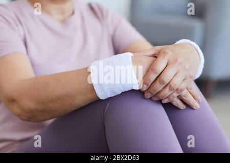 Nahaufnahme einer älteren Frau mit Sportarmbändern an den Händen, die nach dem Sporttraining sitzt und sich ausruht Stockfoto