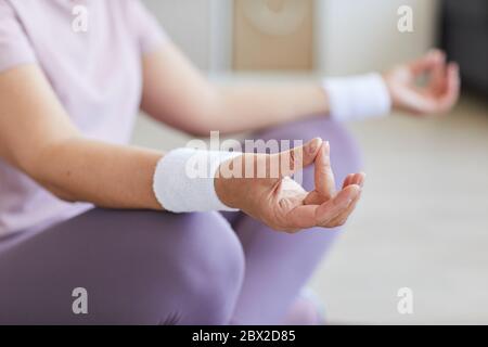 Nahaufnahme einer älteren Frau, die in Lotusposition sitzt und meditiert Stockfoto