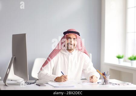 Ruhiger arabischer Mann sitzt an einem Tisch im Büro. A Stockfoto