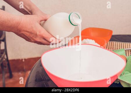 Kochen dünne Pfannkuchen - Kneten Teig - Milch zum Teig hinzufügen Stockfoto