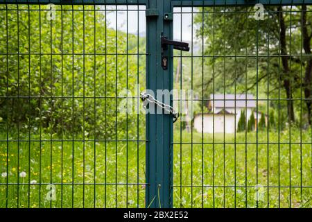 Zaun vom Haus. Bewachung des Grundstücks. Im Hintergrund Grün, Gras und Wiesen Stockfoto