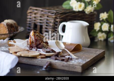 Stück Schokoladenbrownie mit leckeren Karamell auf einem dunklen Holzbrett, Stücke gebrochener Schokolade und einem weißen Milchkrug. Tageslicht Stockfoto