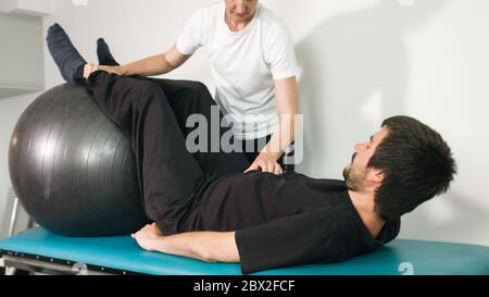 Physiotherapeut mit behinderten Menschen auf einem Therapietisch mit einem Ball trainieren. Stockfoto