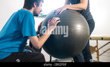 Physiotherapeut mit behinderten Menschen auf einem Therapietisch mit einem Ball trainieren. Stockfoto