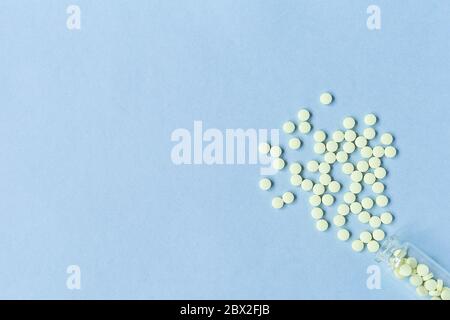 Gelbe Tafeln auf einem pastellblauen Hintergrund. Tabletten und eine Glasflasche auf blauem Hintergrund. Medizin, Gesundheitswesen und Tabletten Konzept. Flatley. Der vi Stockfoto