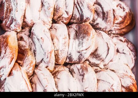 Nahaufnahme von frischen süßen Brötchen mit Puderzucker bestreut in einer Bäckerei - Brotladen - selektive Fokus Stockfoto