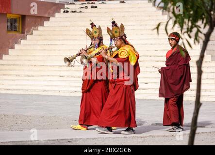 KAZA, Himachal Pradesh, Indien - Mai 2012: Zwei buddhistische Mönche spielen traditionelle Trompeten und gehen während der Mandala-Zerstörung einem Novizenmönch voraus Stockfoto