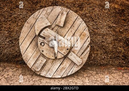 Ein altmodisches Holzrad neben einem Heuhaufen im Himalaya-Dorf Langza im Spiti-Tal in Indien. Stockfoto