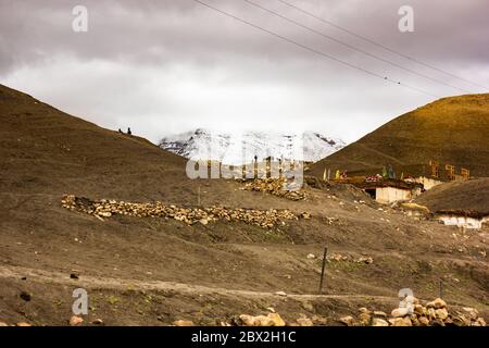 Langza, Himachal Pradesh, Indien - Mai 2012: Eine wunderschöne bukolische Szene des Himalaya-Dorfes mit schneebedeckten Bergen an einem bewölkten Tag. Stockfoto