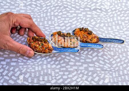Lachsfleisch mit Gewürzen auf dem Tisch. Das Fleisch wird dekorativ in keramischen Löffeln präsentiert. Stockfoto