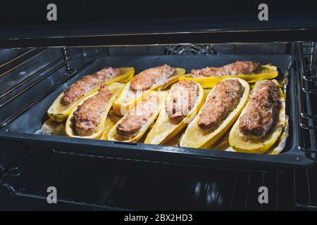 Zusammen mit Zucchini geschnitten, die während des Backens mit Hackfleisch auf einem Backblech im Ofen gefüllt sind Stockfoto