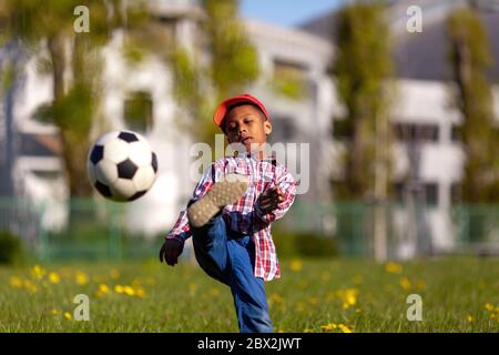 Kleiner Junge schießen auf goal.Young african american Fußballspieler treten einen Fußball auf einem Grasfeld. Stockfoto