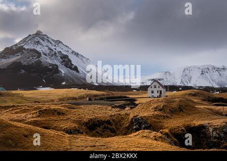 Einsames Haus an der Basaltküste und dem Stapafell-Berg nahe dem snfellsjoekull-Gletscher, Arnarstapi, Snaefellsnes, Island Stockfoto