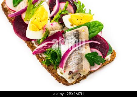 Eingelegtes mariniertes Hering und Rote Bete offenes Sandwich auf Roggenbrot. Traditionelles dänisches Smorrebrod auf weißem Hintergrund Stockfoto