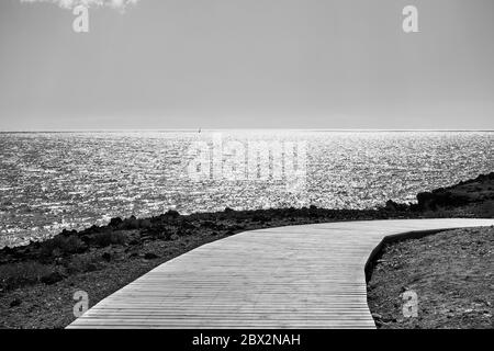 Biegende hölzerne Fußpfad am Meer - schwarz-weiße Landschaft Stockfoto