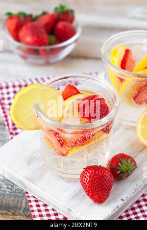 Erfrischende hausgemachte Limonade mit frischer Erdbeere, Zitrone und Eis. Gesunde kalte Getränke, wenig Kalorien. Leckeres kühles Sommergetränk. Weißer Holzhintergrund Stockfoto