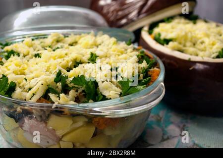 Kartoffeln in Töpfen zum Backen vorbereiten. Kartoffeln, Fleisch, Zwiebeln, Karotten, Petersilie, Käse, Pilze in Glas und Keramikgefäßen. Bereit zum Backen. Ru Stockfoto