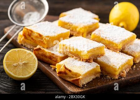 Hausgemachte Zitronenriegel mit Mürbeteig-Kruste, auf Holzhintergrund. Stockfoto