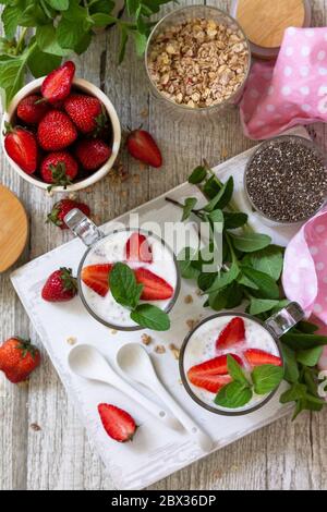 Gesundes Essen Konzept Frühstück. Erdbeerparfait mit Joghurt, Chiasamen, hausgemachtem Müsli und frischen Beeren auf einer Steinbetonarbeitspfläche. Draufsicht Stockfoto