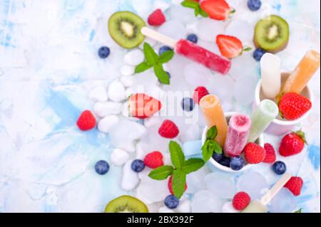 Hausgemachte Erdbeerpopsicles mit Eis, verschiedenen Beeren und Minze. Sommer gesundes Essen Konzept mit Kopierraum. Fruchteis mit verschiedenen Geschmacksrichtungen. Stockfoto