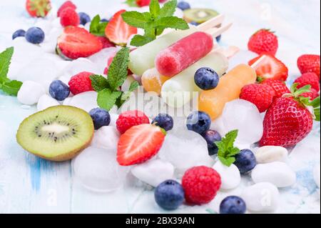 Hausgemachte Erdbeerpopsicles mit Eis, verschiedenen Beeren und Minze. Sommer gesundes Essen Konzept mit Kopierraum. Fruchteis mit verschiedenen Geschmacksrichtungen. Stockfoto