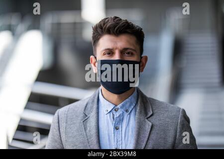 Junger Geschäftsmann im Büro trägt chirurgische hygienische Schutzmaske im Gesicht. Idee zur Prävention der Krise des Coronavirus und Gesundheitsversorgung für die Sicherheit der Arbeit Stockfoto