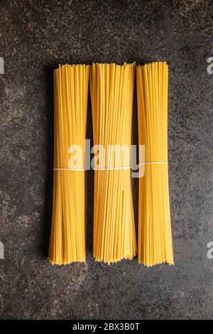 Rohe italienische Spaghetti-Pasta auf schwarzem Tisch. Draufsicht. Stockfoto