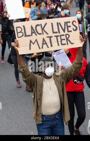 Ein Mann, der während des marsches bei der Black Lives Matters-Demonstration in London, 3. Juni 2020, eine Gesichtsmaske trägt und ein Schild hält Stockfoto